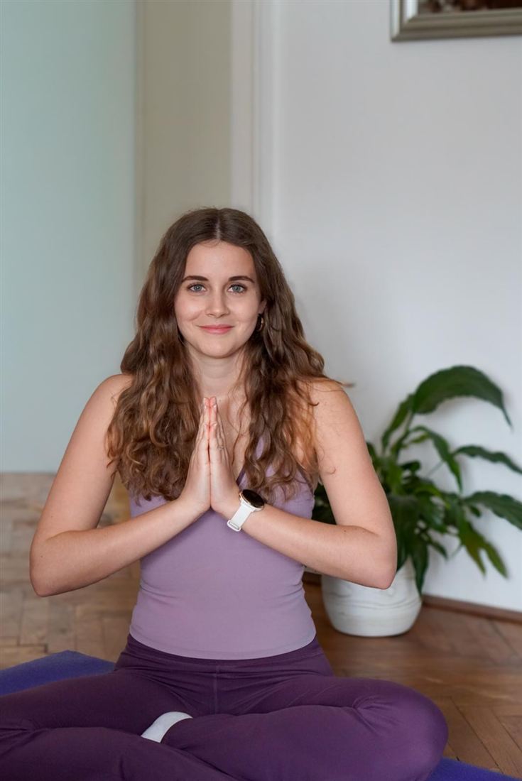Julie Fornara, Yogalehrerin bei MAHANA Yoga in Klagenfurt, sitzt ruhig mit gefalteten Händen